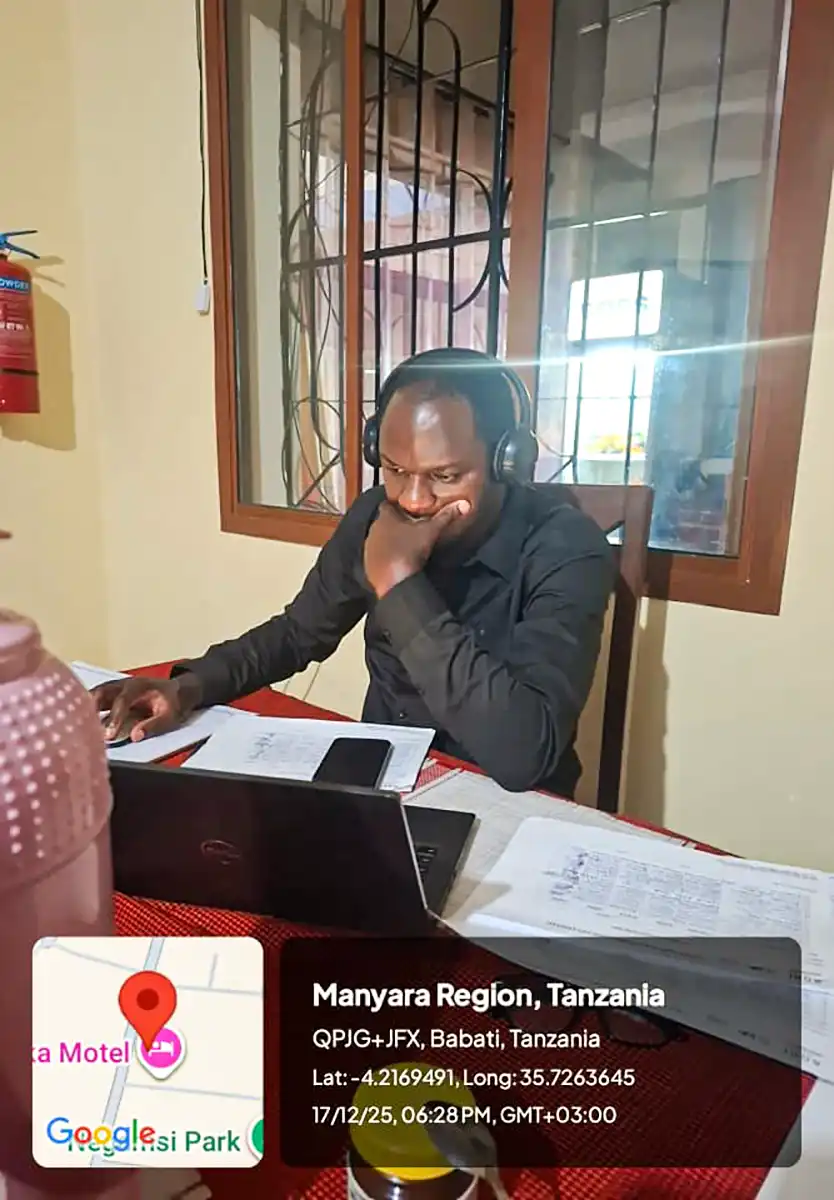 A person works at a table; a precise location and timestamp overlay appears at the bottom.