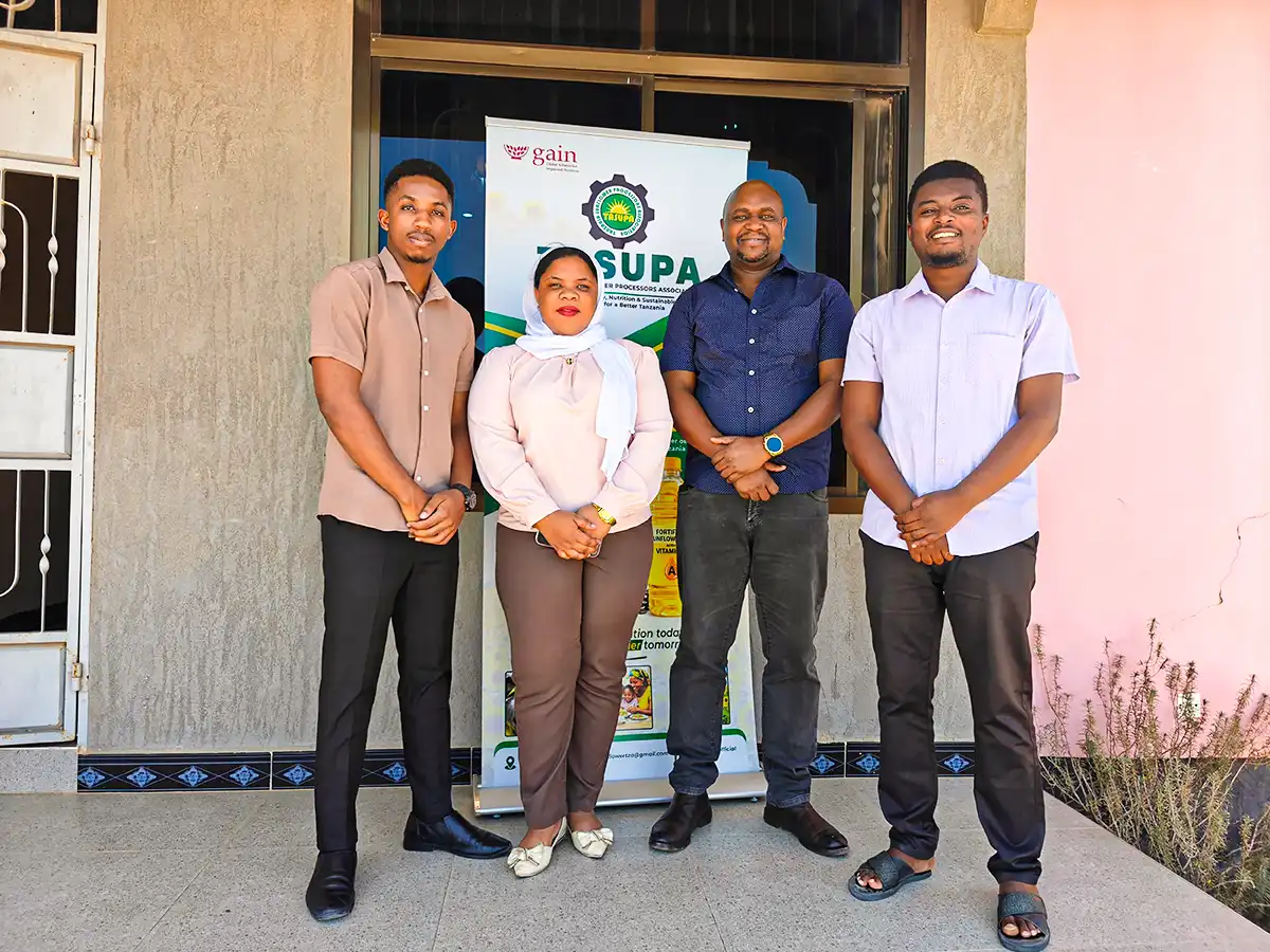 Four people stand together in front of a TASFOPA banner.